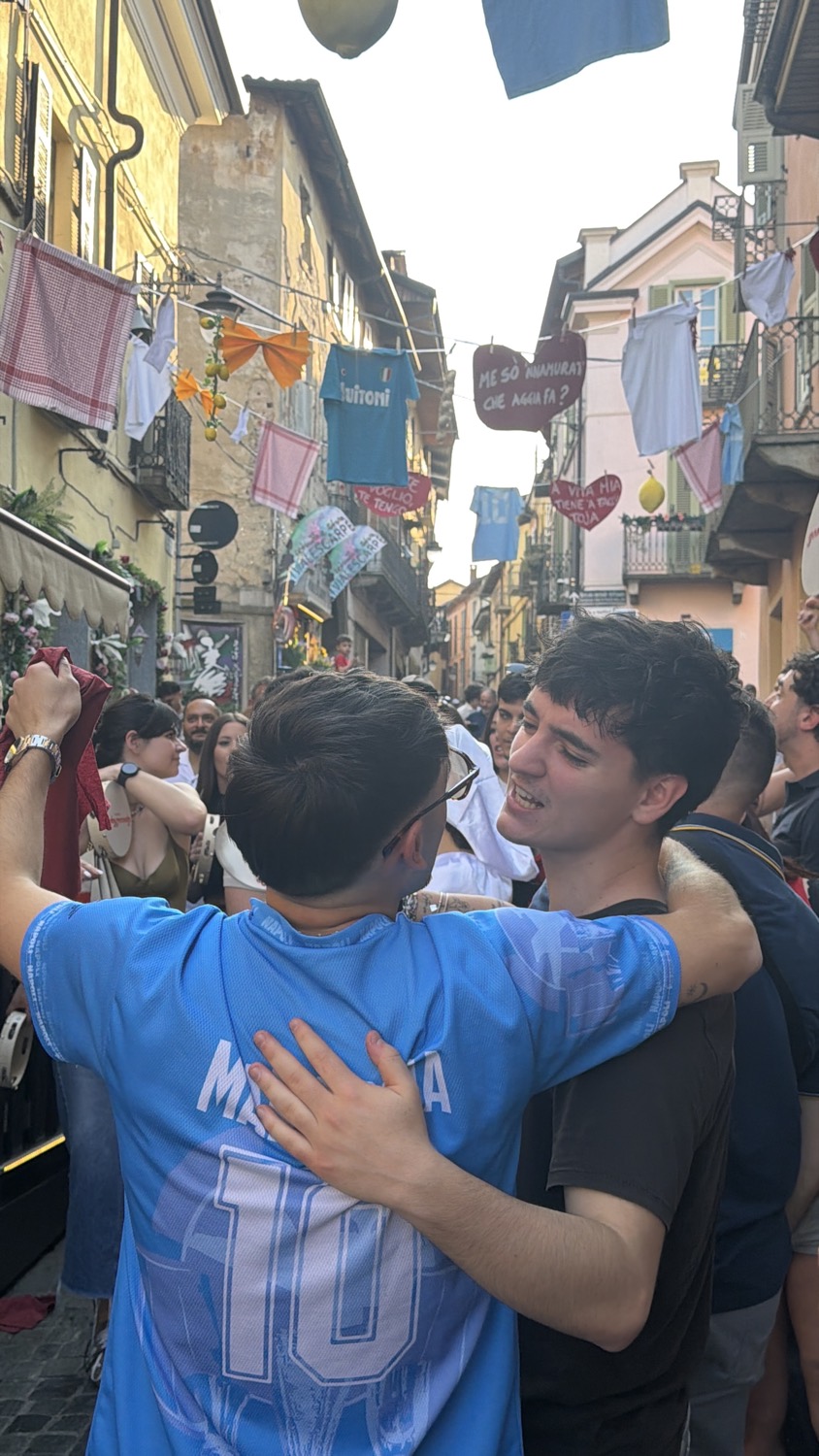 Due ragazzi si abbracciano in mezzo alla festa, uno con la maglia numero 10