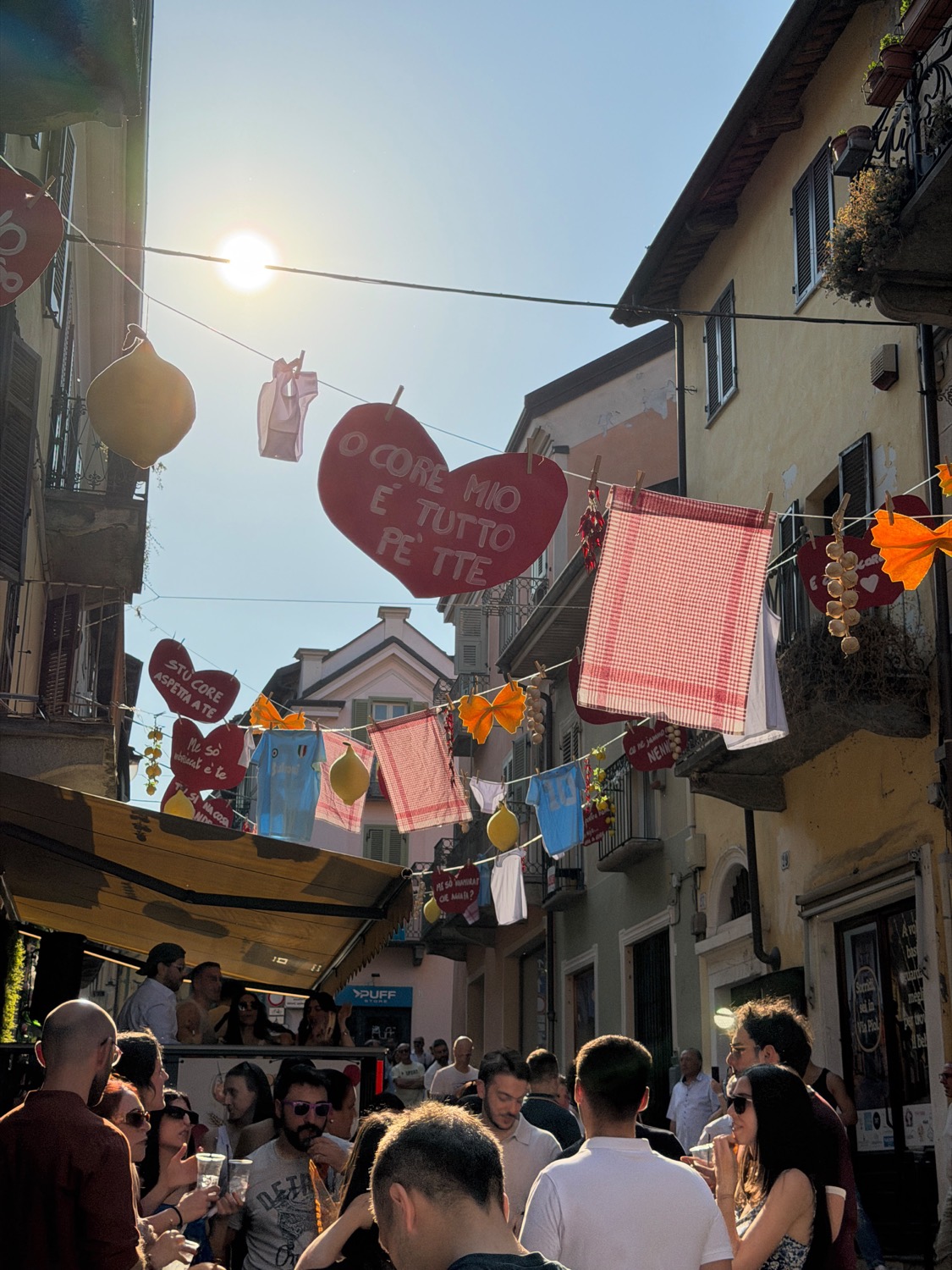 Gente ai tavoli sotto i cuori appesi al tramonto