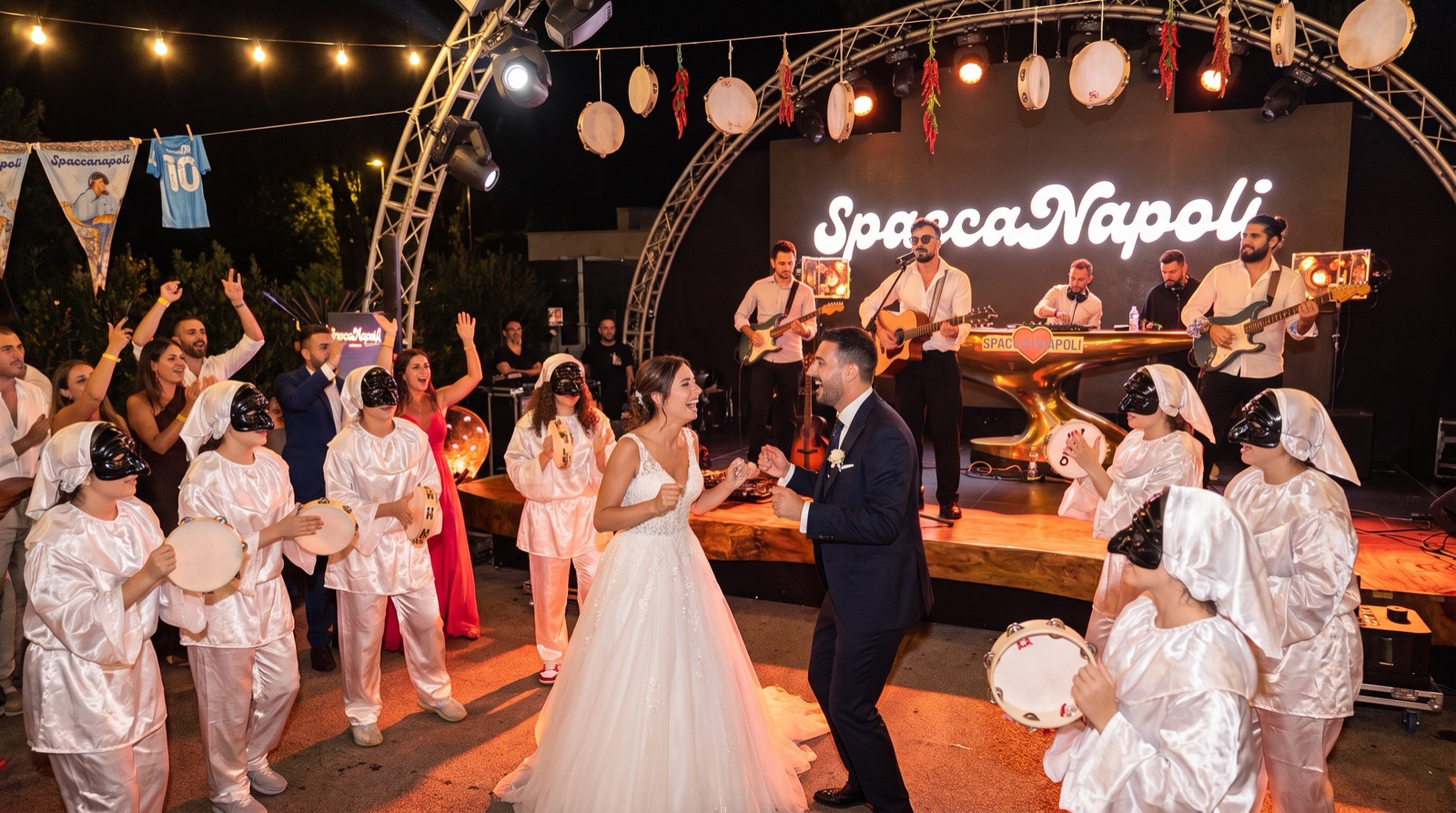 Gli sposi ballano circondati dai Pulcinella con le tammorre, con la band SpaccaNapoli sul palco
