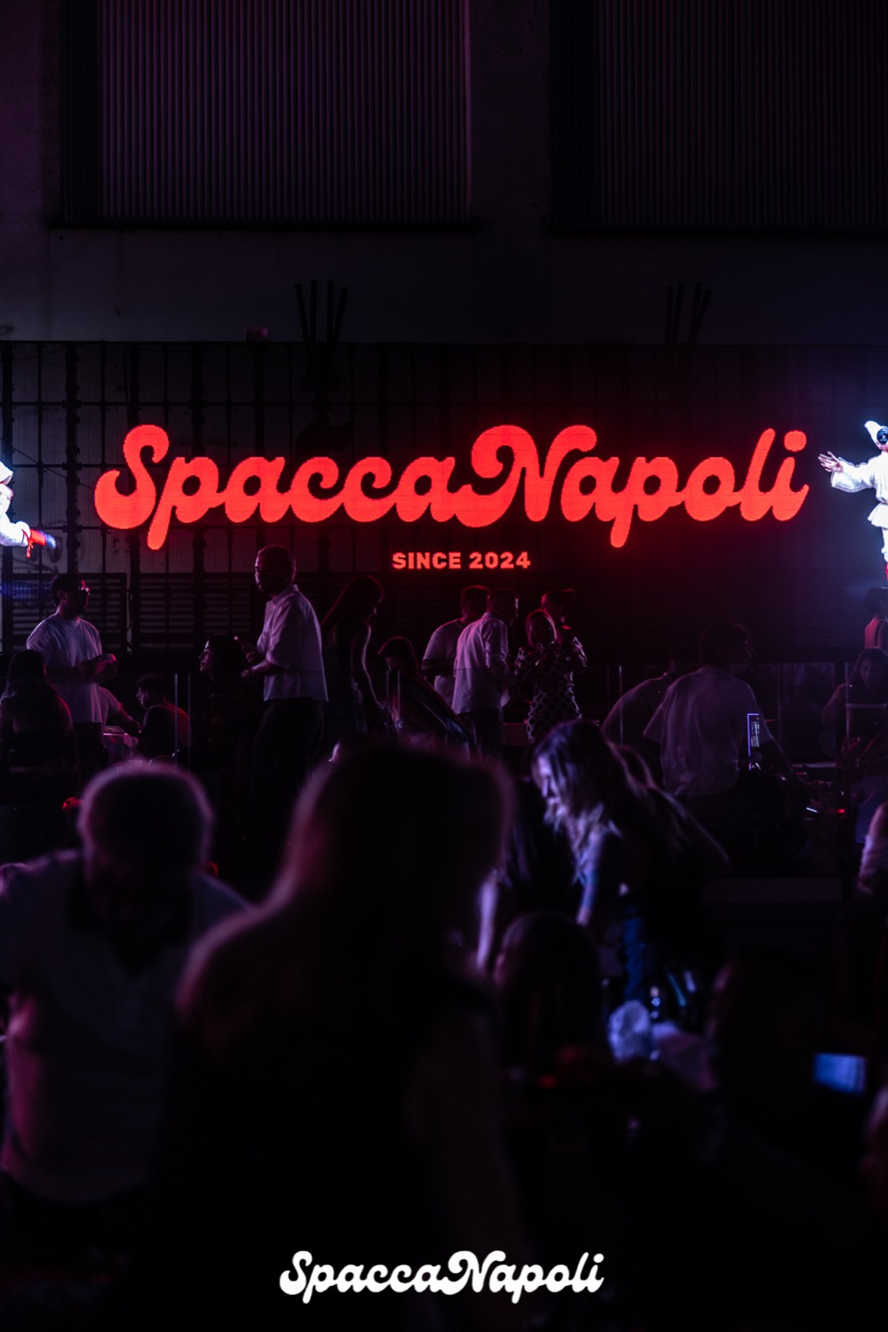 La folla sotto l'insegna al neon di una serata sold out